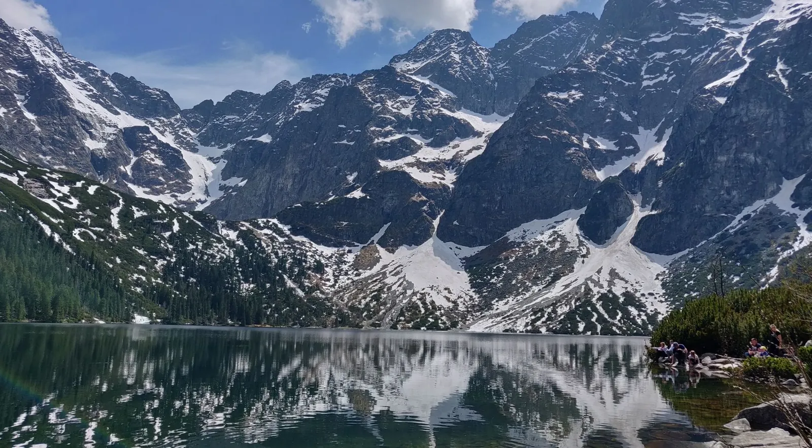 A glacial lake below snow-streaked granite walls in late spring