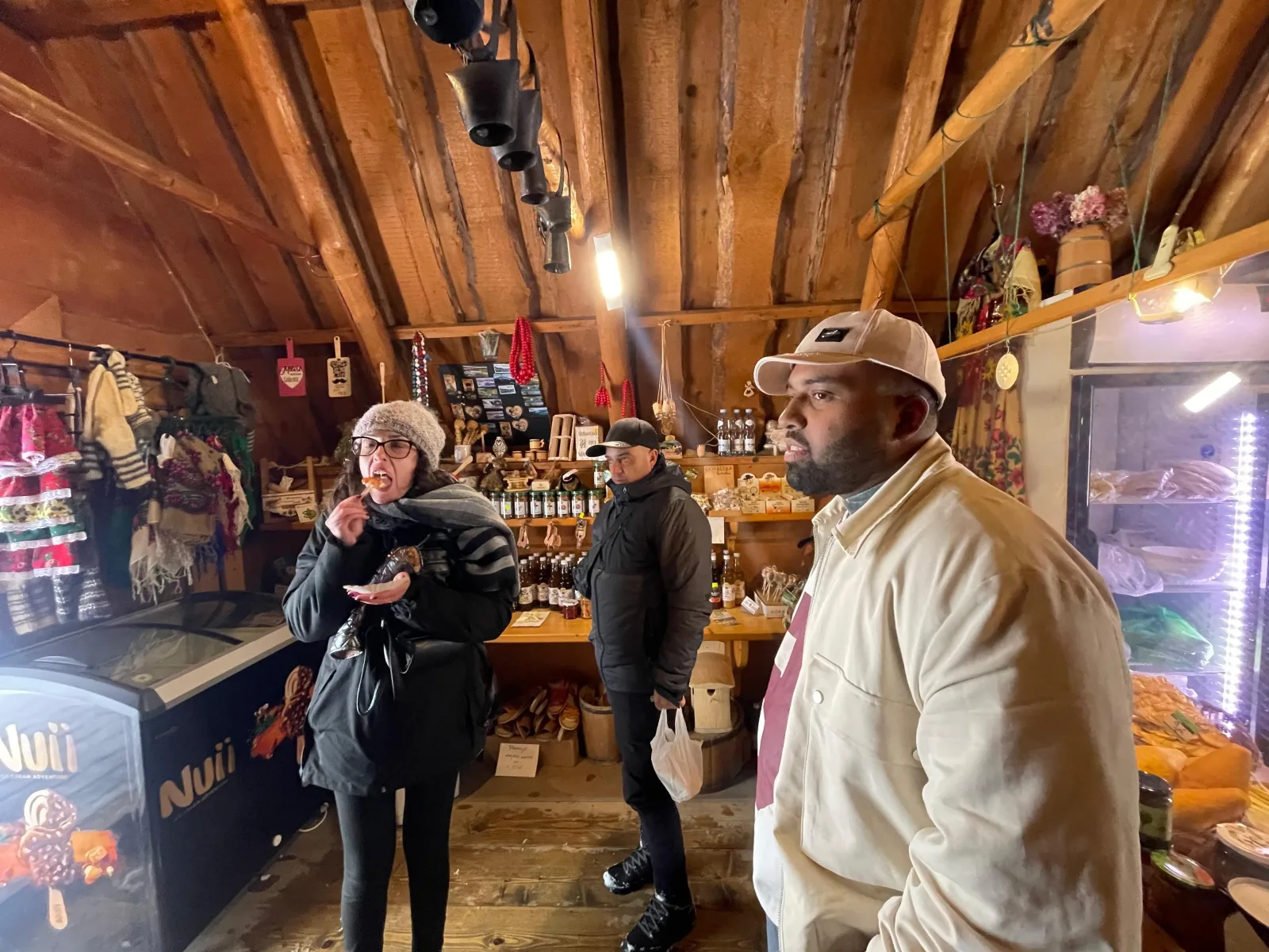 Visitors tasting snacks inside a wooden highland souvenir and food shop