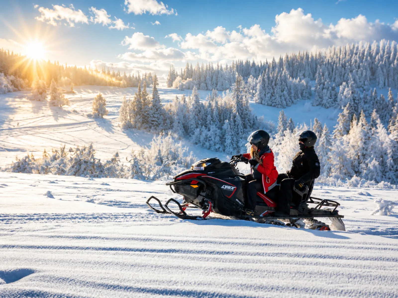 Two riders on a red and black snowmobile on a sunny snowy hillside