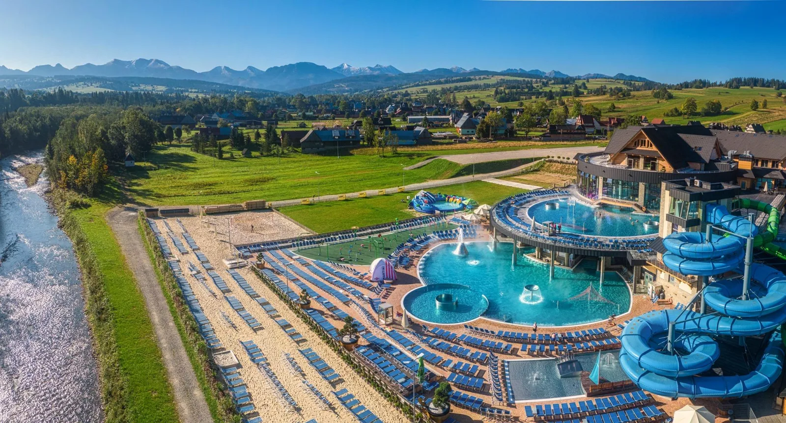 Aerial view of outdoor thermal pools and water slides below the Tatras