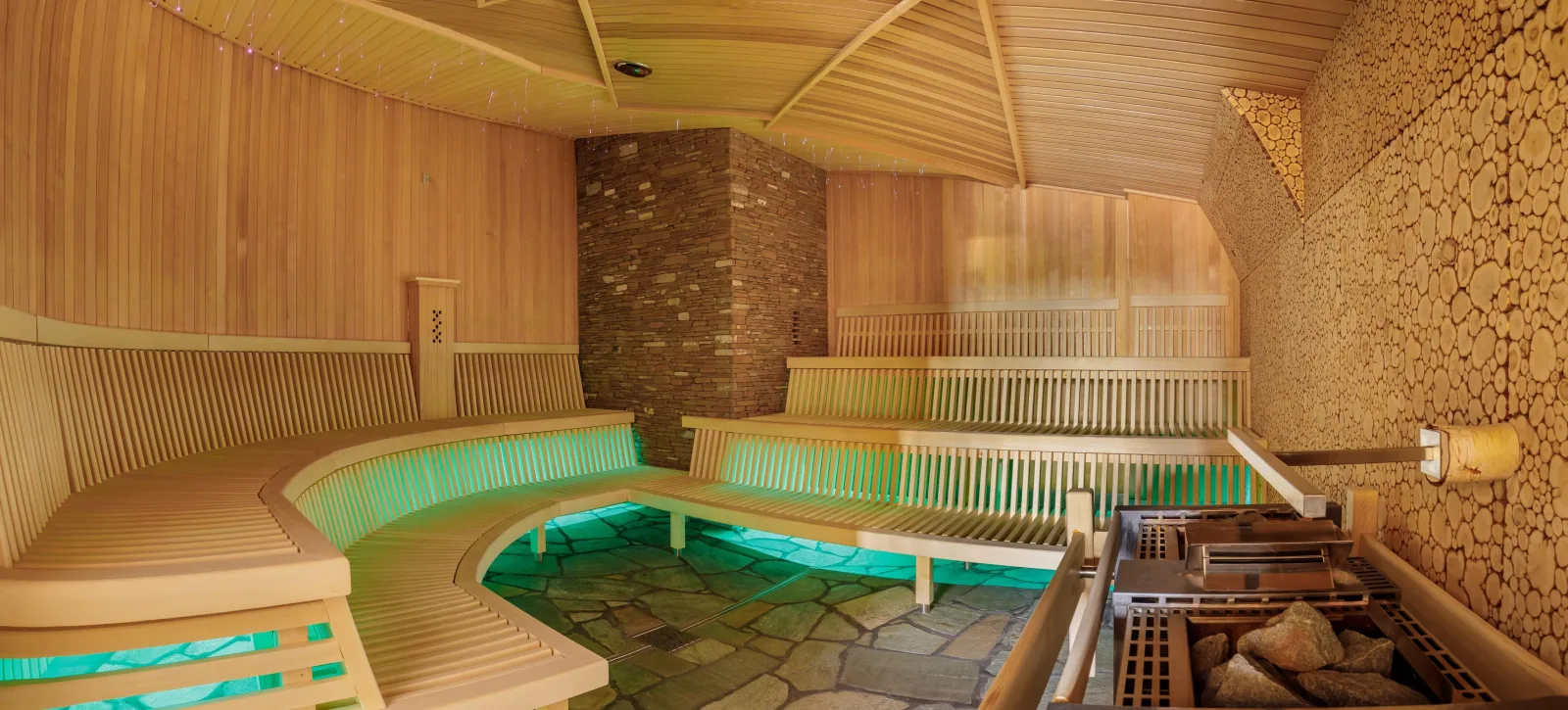 Empty wooden sauna with curved benches and green under-lighting