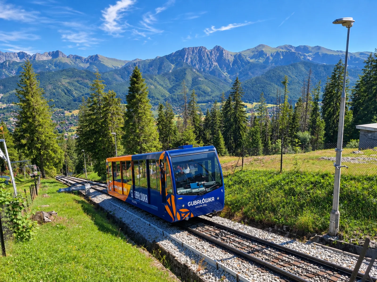 Blue Gubałówka funicular car climbing the track with Tatra peaks behind