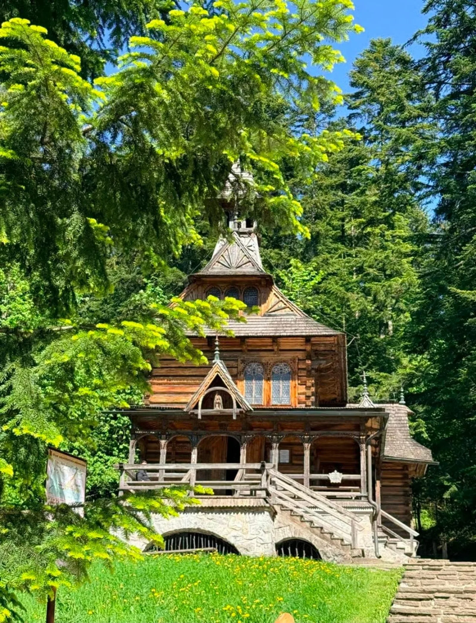 Wooden Jaszczurówka Chapel among tall conifers in spring sunshine