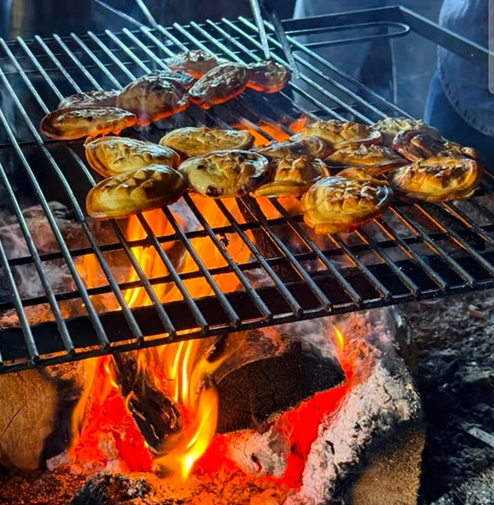 Small smoked cheeses grilling over an open wood fire