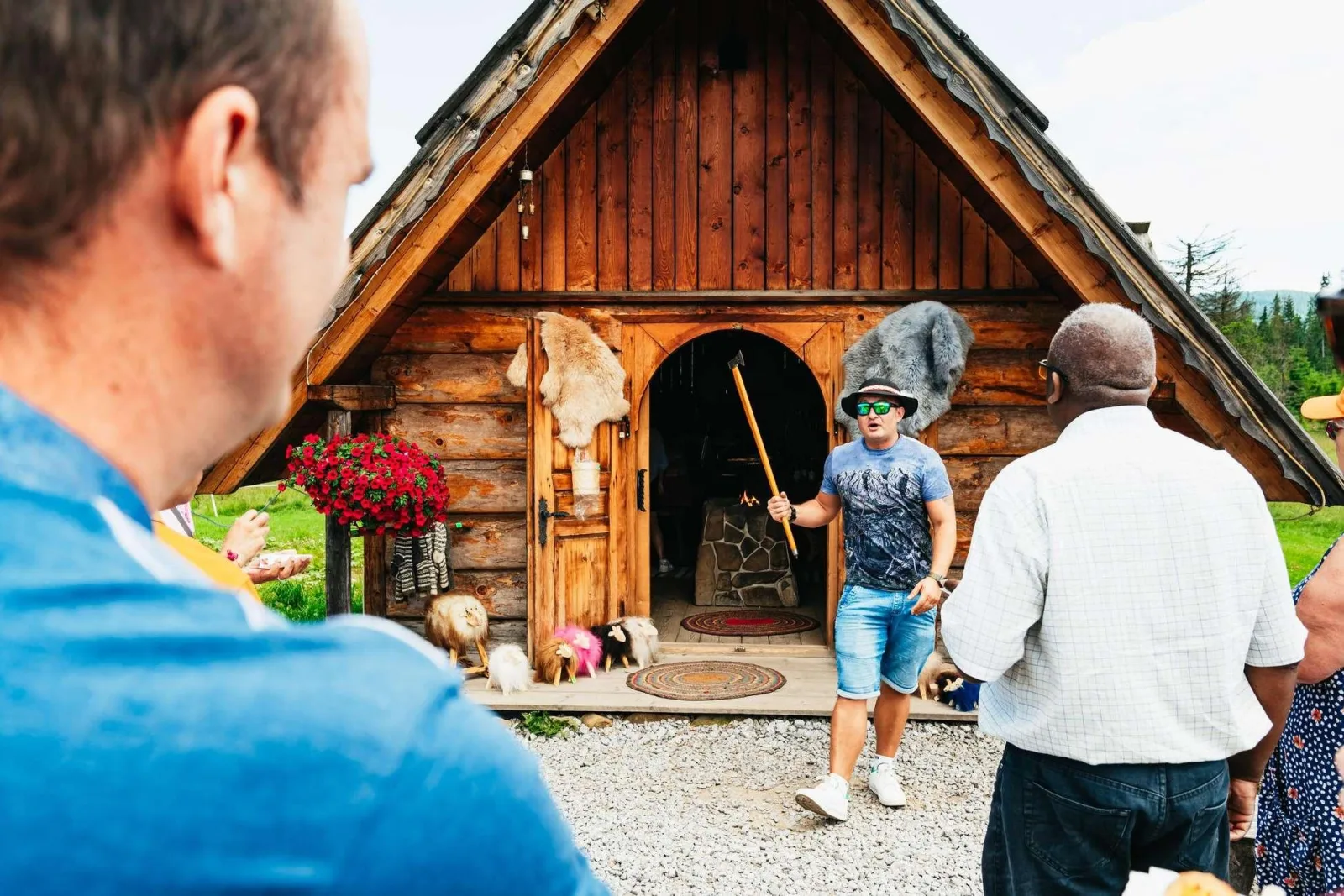 Host in a hat talking to visitors outside a wooden shepherd's hut