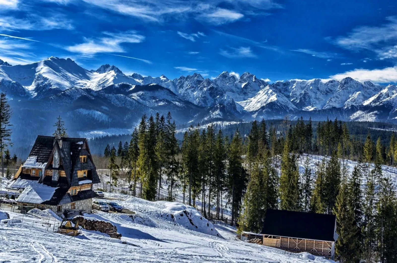 Snow-covered wooden houses below a snowy Tatra mountain range