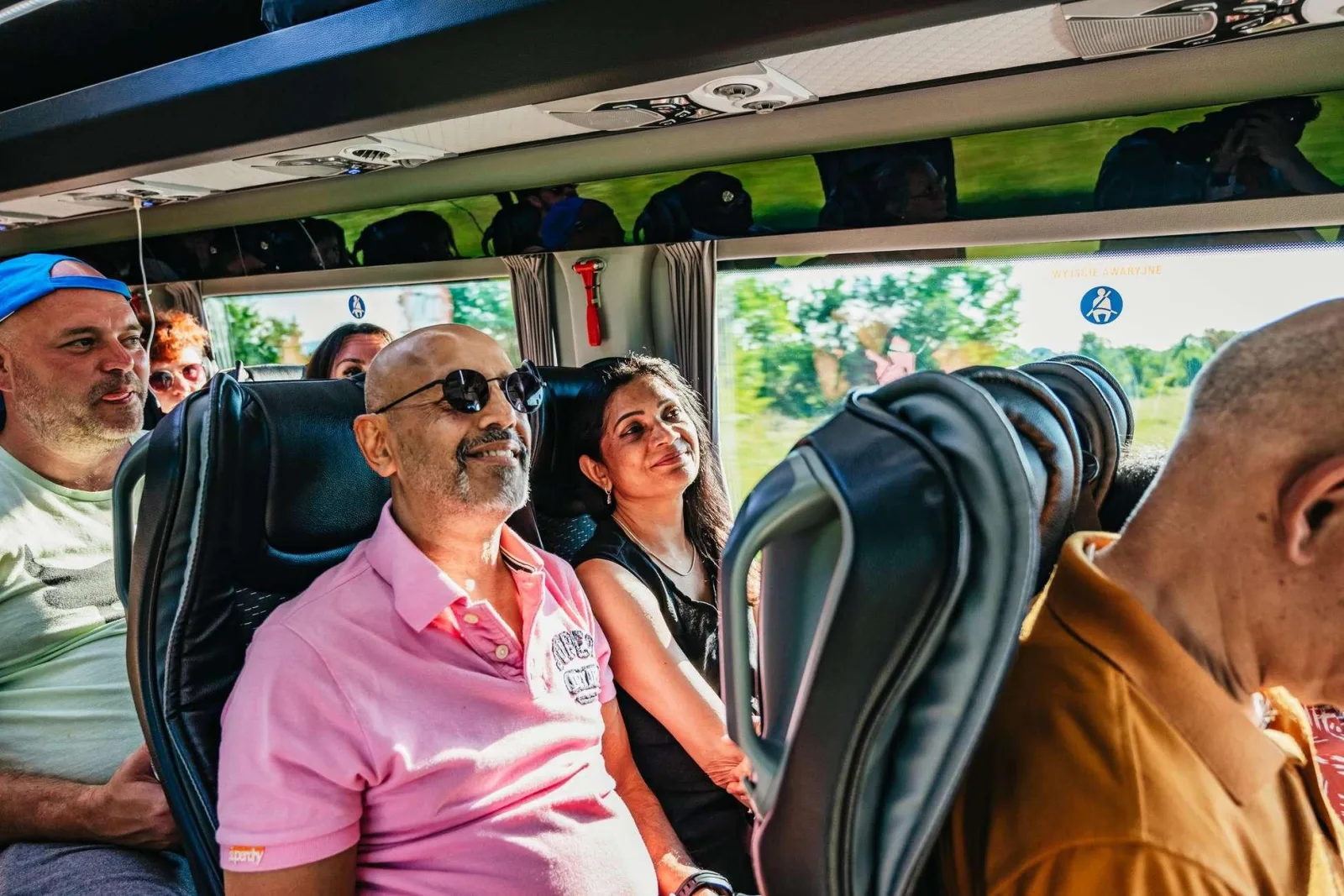 Smiling passengers seated inside an air-conditioned tour minibus
