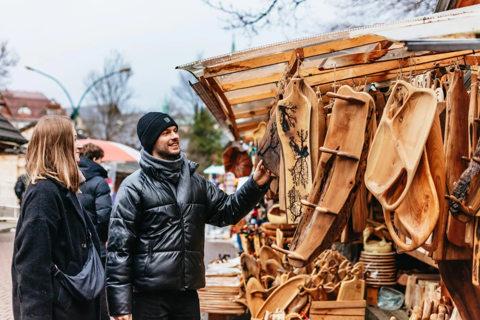 Couple browsing carved wooden boards at a market stall