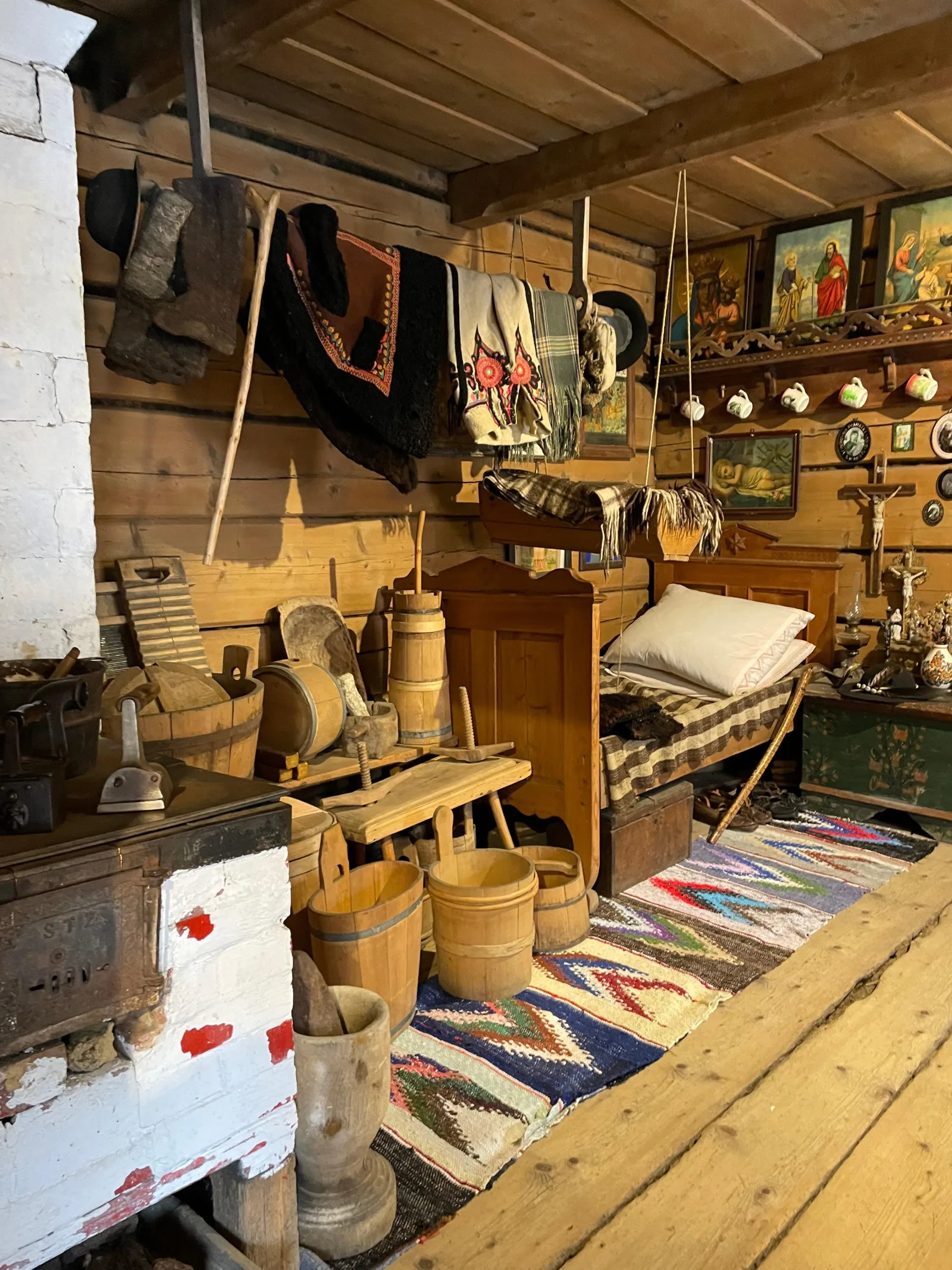 Highlander cottage interior with carved shelf, holy pictures, bed and wooden tubs