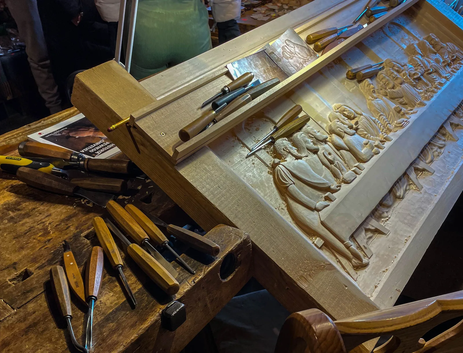 Carving chisels on a workbench beside a half-finished wooden relief