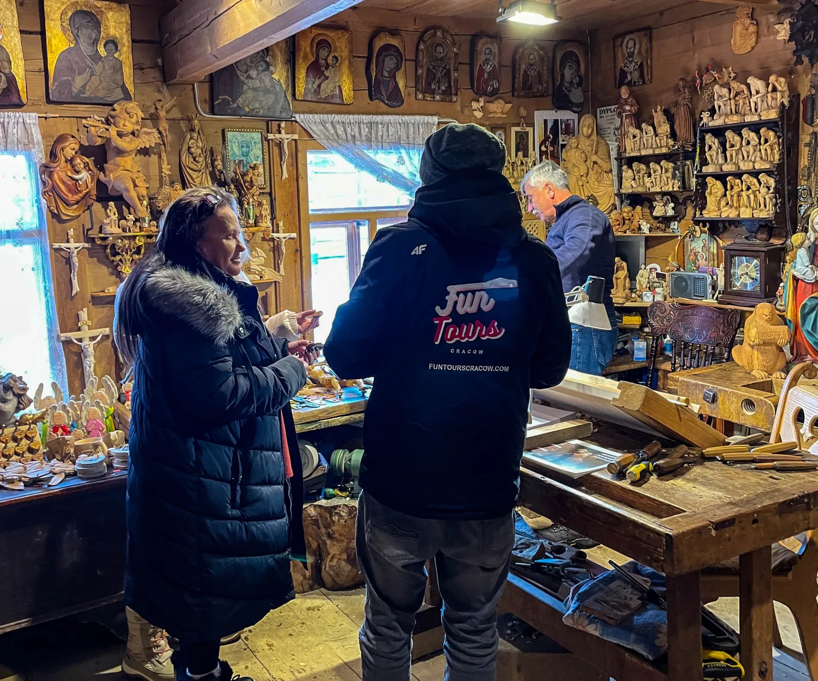 Guide and visitor inside a woodcarver's workshop full of carved figures