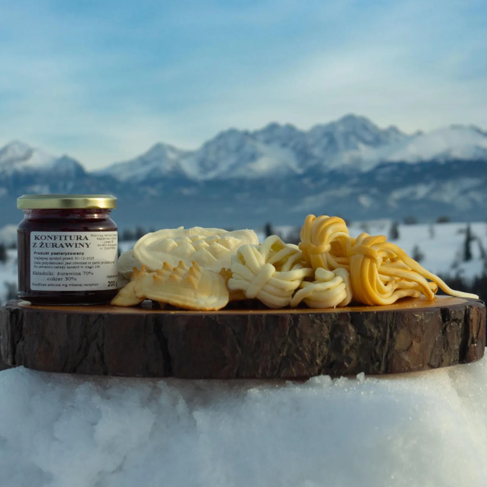 Smoked cheeses and a jar of cranberry jam with snowy peaks behind