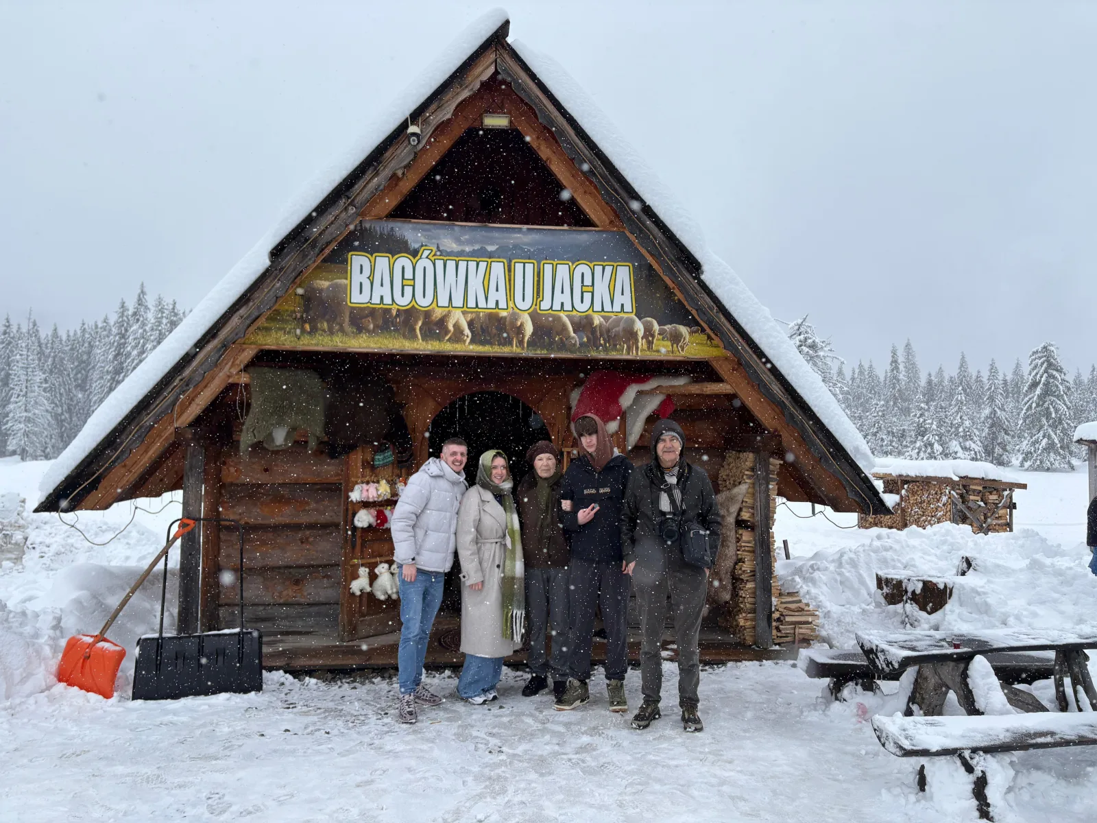 Group standing outside the snow-covered Bacówka u Jacka wooden hut