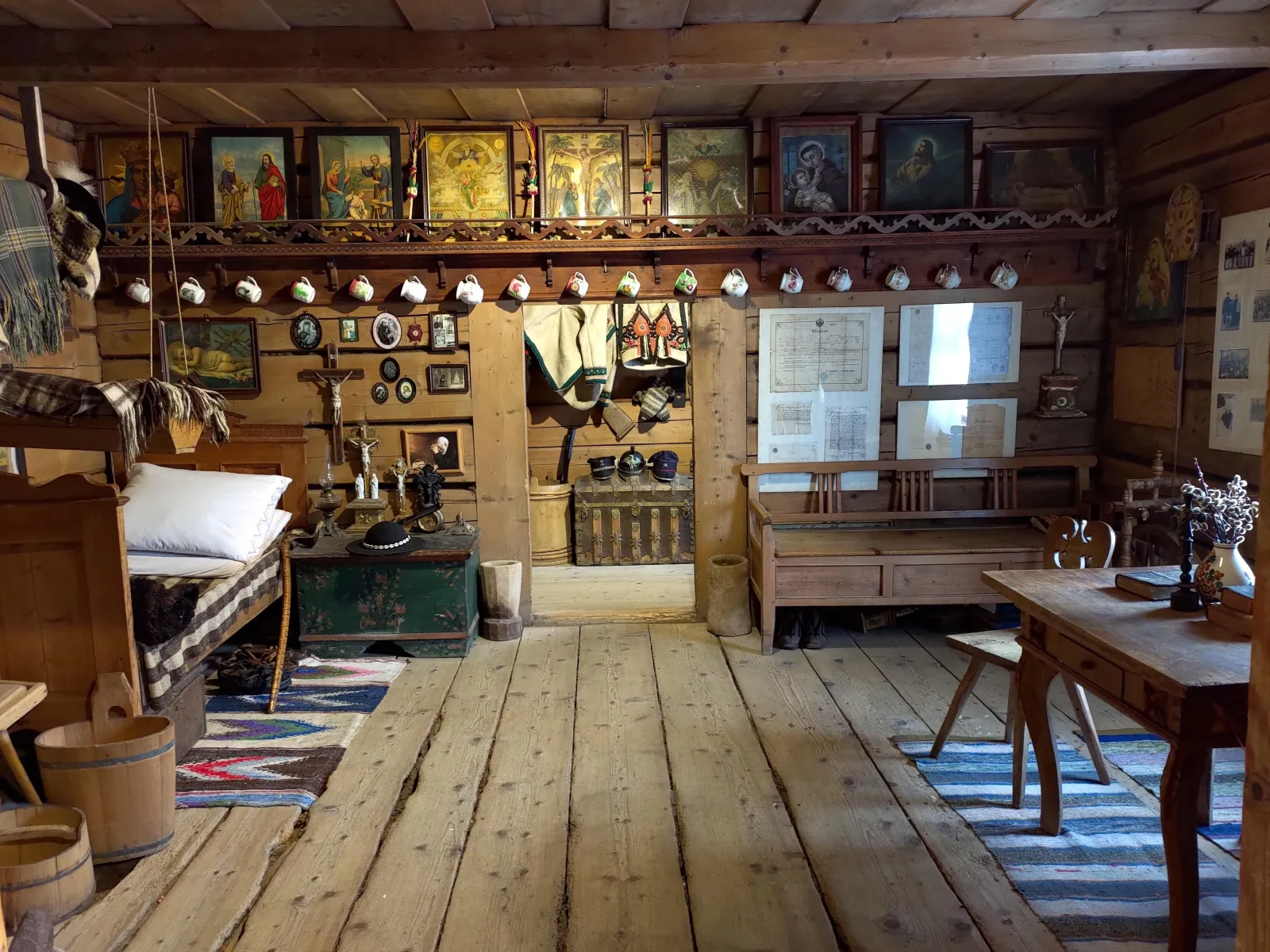 Highlander log house interior with holy pictures, bed, chest and benches