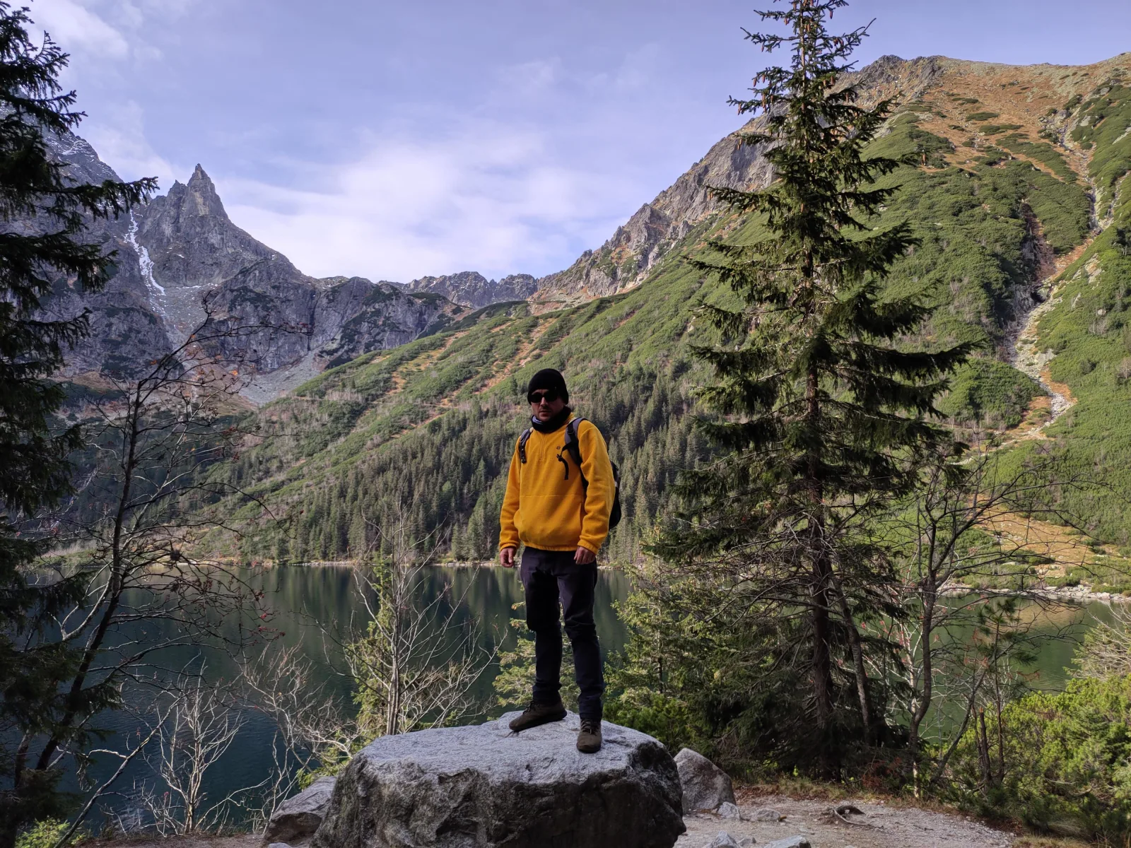 Hiker standing on a boulder above Morskie Oko lake and rocky peaks