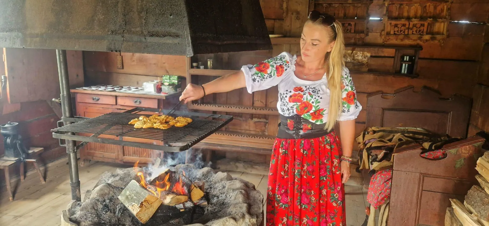 Woman in highland costume grilling cheese over an open fire indoors