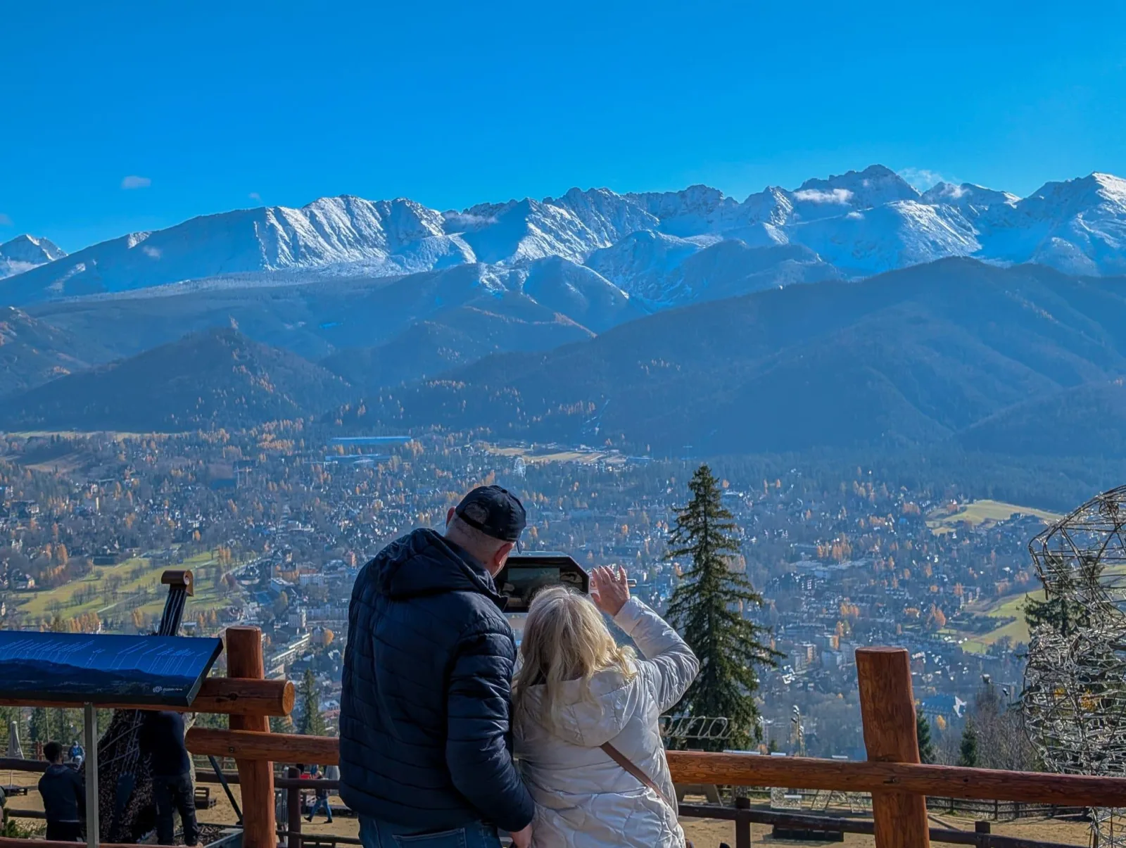 Couple at a viewing platform above Zakopane with snowy Tatras behind