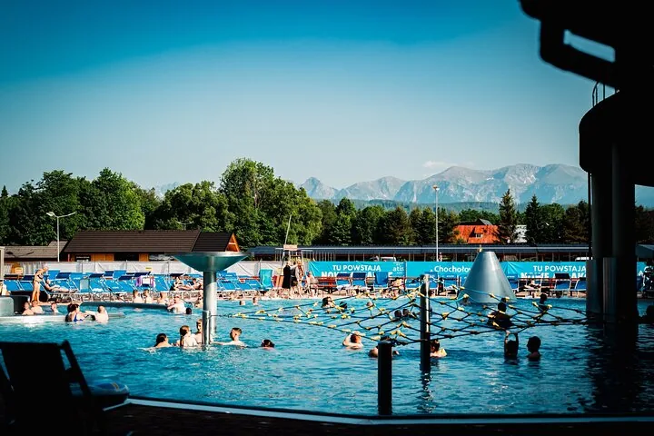Bathers in a large outdoor thermal pool with mountains on the horizon