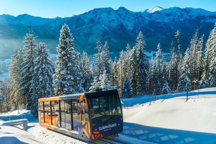 Gubałówka funicular car climbing through snowy fir trees below the Tatras