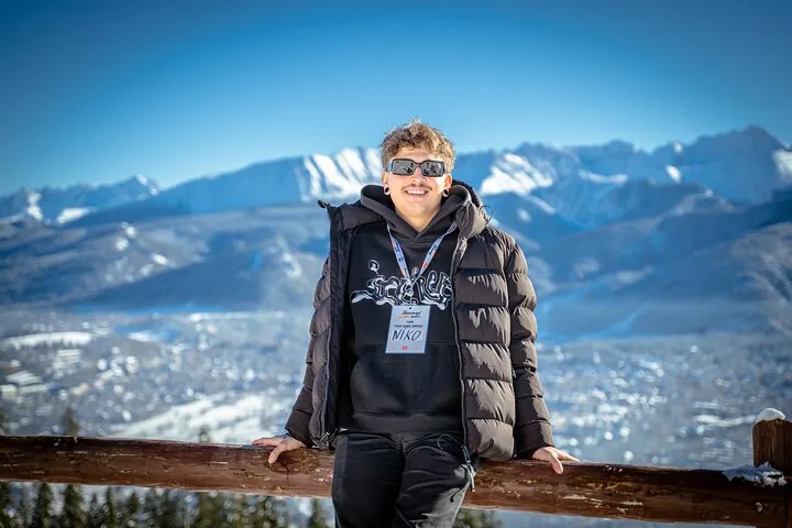 Traveller leaning on a wooden rail with snowy Tatra peaks behind