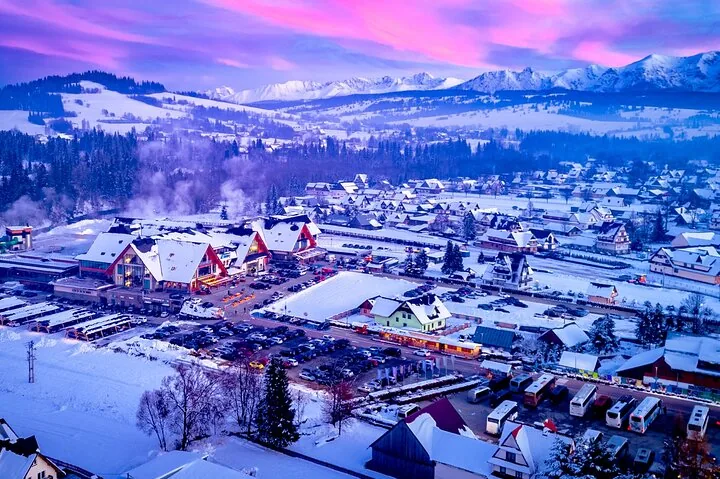 Snow-covered mountain village at dusk under a pink sky