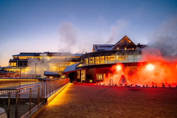 Thermal baths building at dusk with steam rising from the outdoor pools