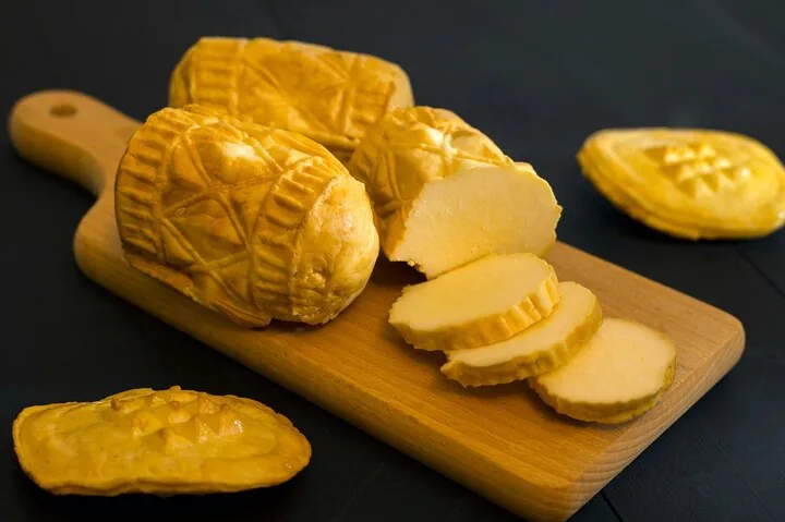 Sliced patterned smoked sheep's-milk cheese on a wooden board