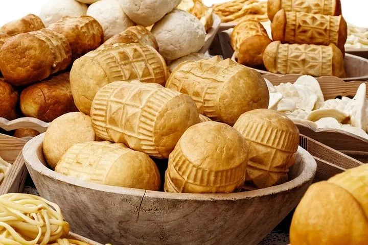 Wooden bowl of patterned smoked sheep's-milk cheeses on a market stall