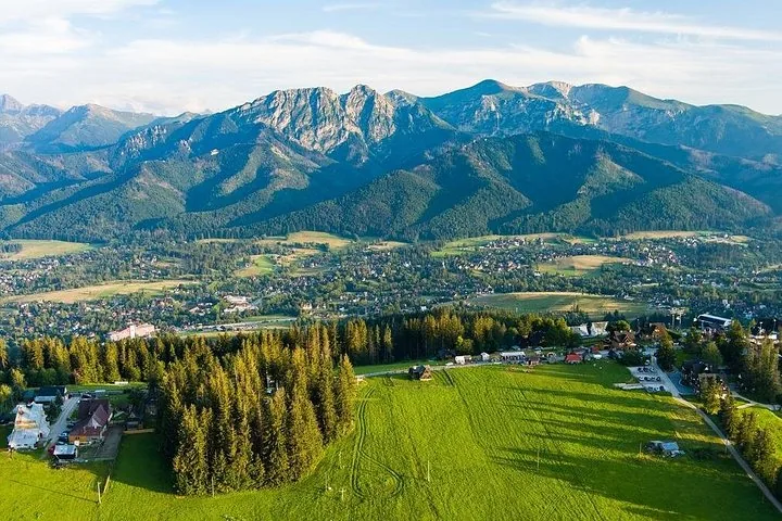 Summer aerial view over green meadows and a town to the Tatras