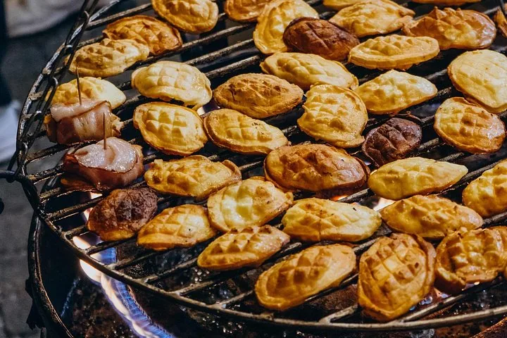 Rows of small patterned cheeses grilling on a round grate