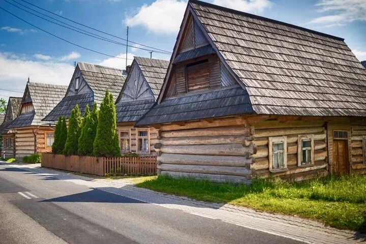 Row of wooden log houses with shingle roofs along a village street