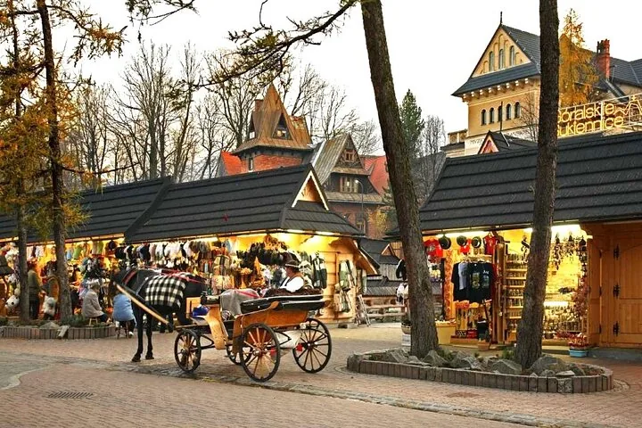 Horse-drawn carriage beside lit wooden souvenir stalls on a street