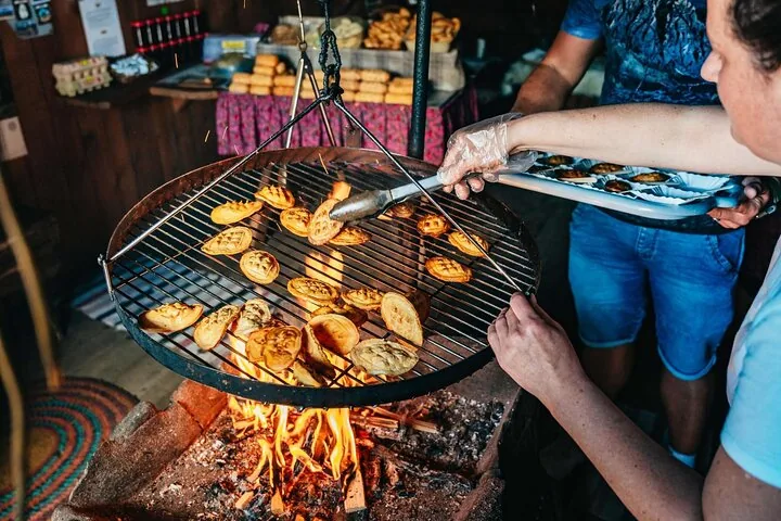 Cheeses grilling on a round grate over a wood fire indoors