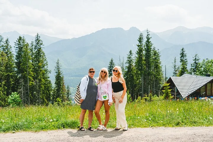 Three friends posing on a path with forested mountains behind