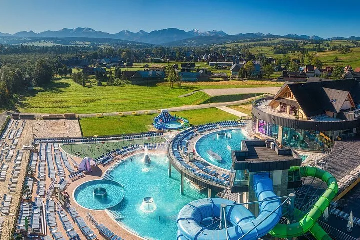 Aerial view of outdoor pools and water slides with mountains behind