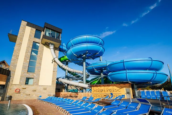Blue and green spiral water slides beside a tall stone tower