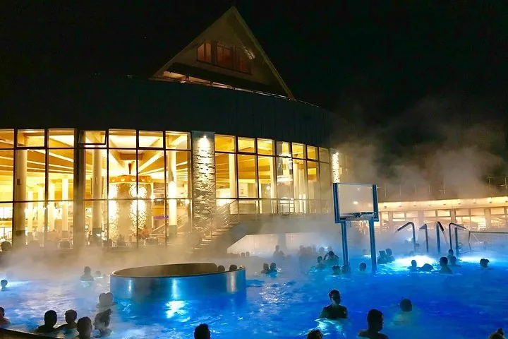 Crowd of bathers in a misty outdoor pool at night