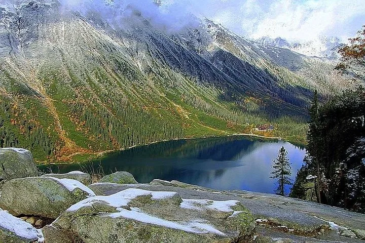 Mountain lake seen from snow-dusted boulders on an autumn day