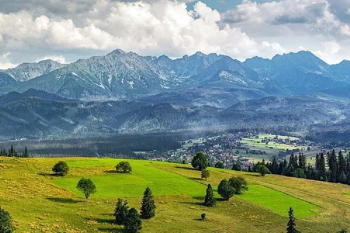 Green hillside meadows above a valley town and mountain range