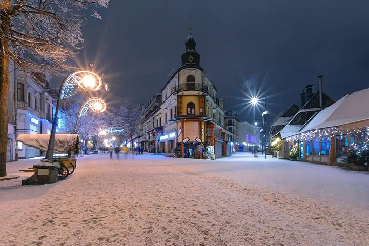Snow-covered pedestrian street with lit lamps at night