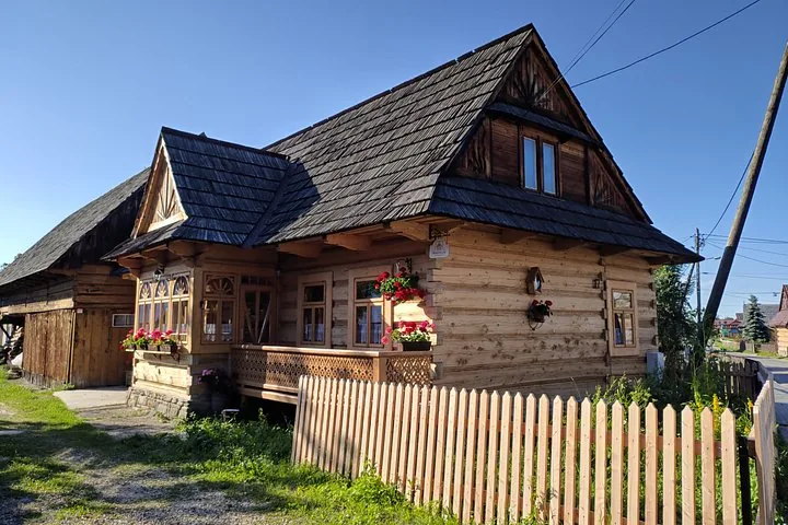 Wooden highland cottage with flower boxes behind a picket fence